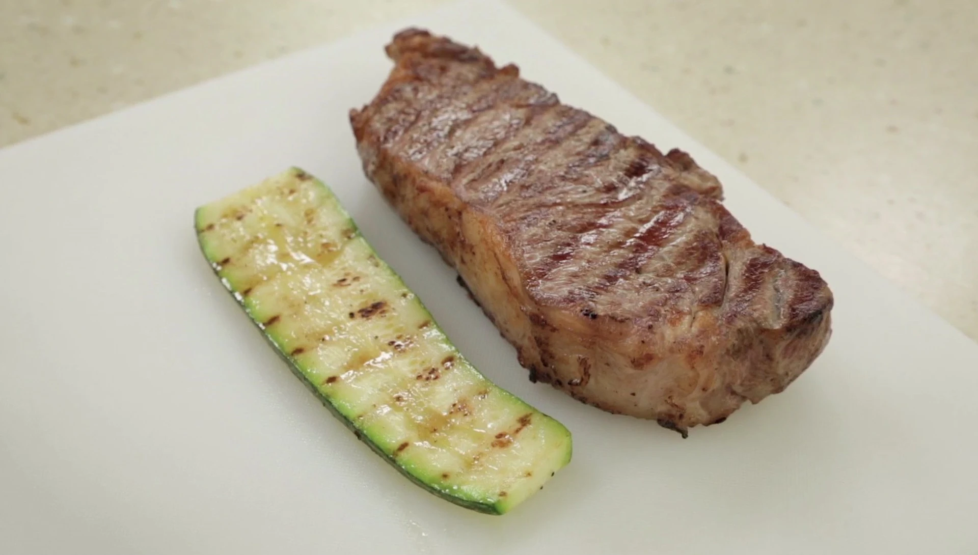 Grilled steak and zucchini, showing grill marks.