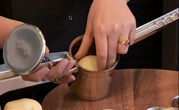 Démonstration de l'insertion d'une pomme de terre dans le presse-purée.